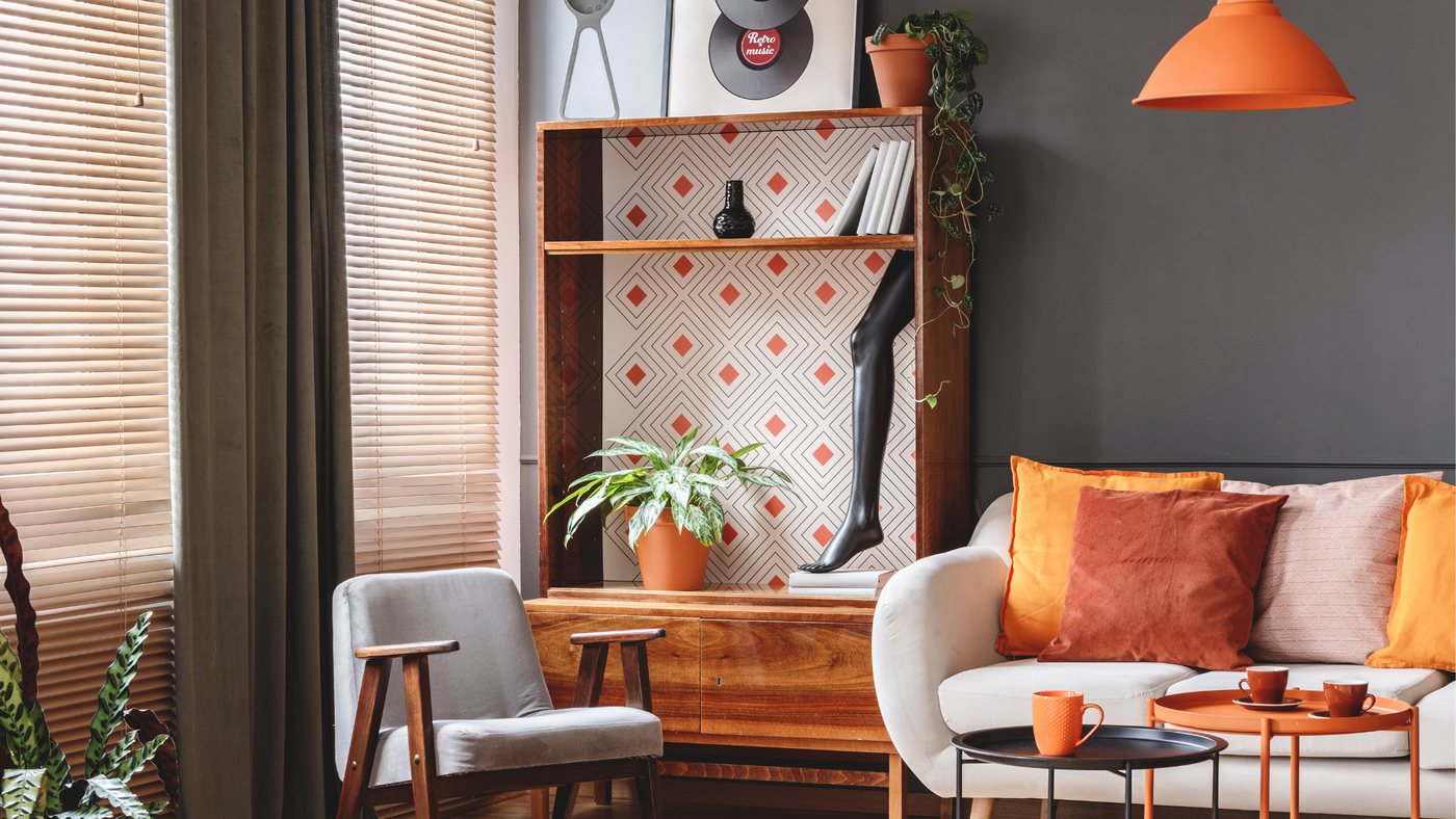 Art deco living room with patterned wallpaper, a built-in shelving alcove and a bright orange pendant lamp
