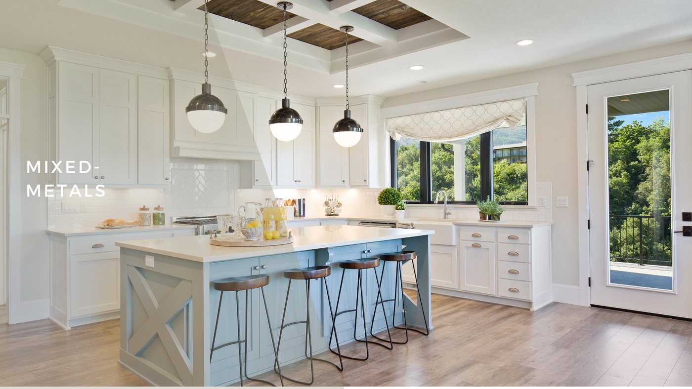 White kitchen with a blue island, counter stools and dark pendant lights